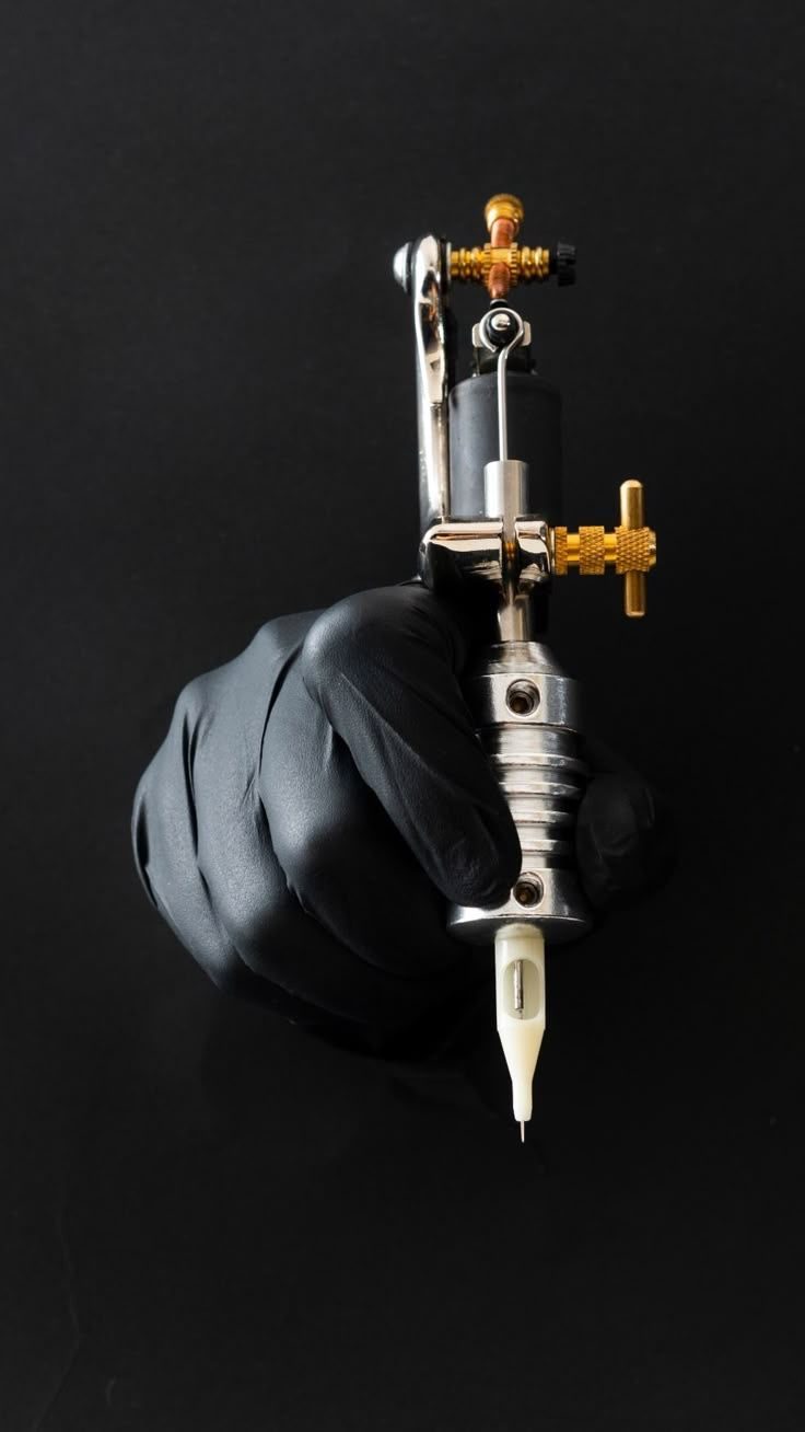 Gloved hand holding a tattoo machine against a black background