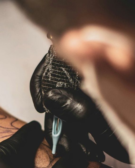 Close-up of a gloved hand tattooing