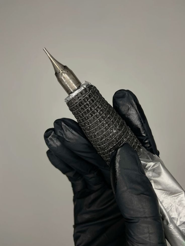 Gloved hand holding a tattoo pen